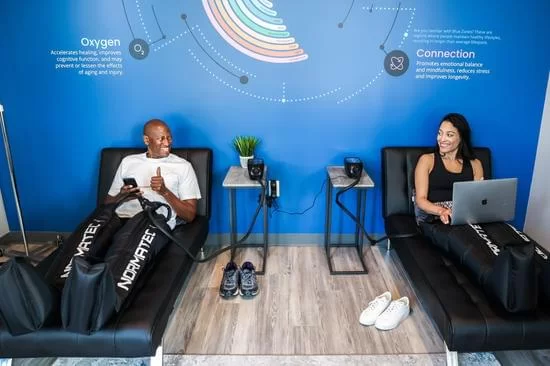 Woman and man smiling while enjoying Leg Compression treatment at Restore