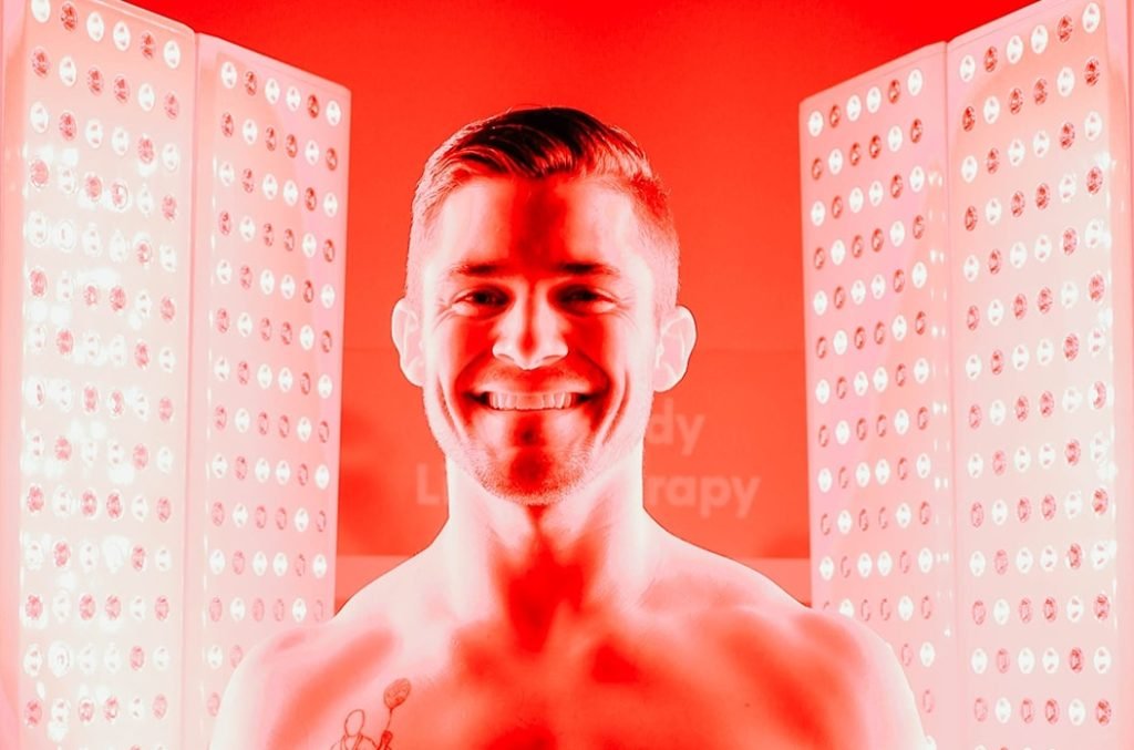 Man smiling while receiving Red Light Therapy at Restore Hyper Wellness