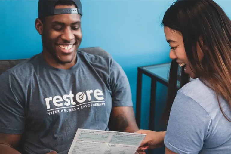 a woman and a man smiling while reading a pamphlet.